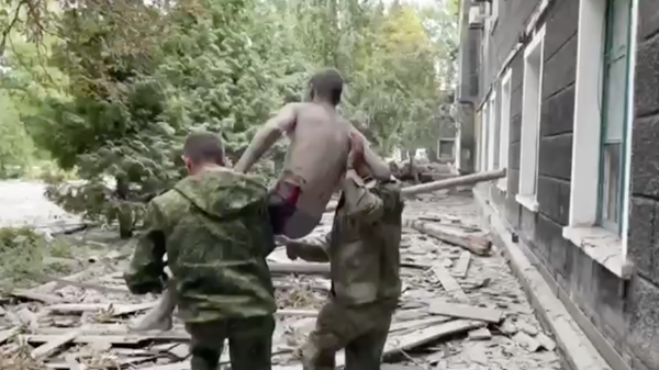 Спасатели вытаскивают пострадавшего при обстреле Перевальского колледжа в ЛНР