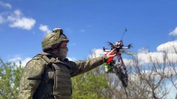 Российский военнослужащий запускает дрон с закрепленными цветами. Кадр видео