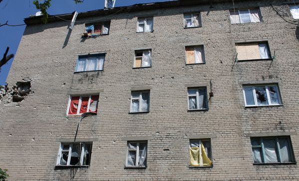 Окна без стекол в пострадавших от обстрелов жилых домах в Донецке