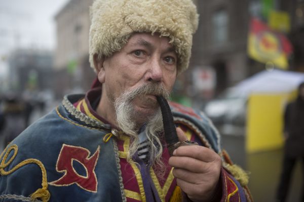 Мужчина в национальном костюме курит трубку на площади Независимости в Киеве Мужчина в национальном костюме курит трубку на площади Независимости в Киеве